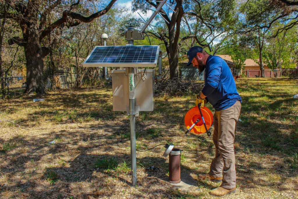 BSEACD staff measures Lovelady Monitor well with an e-line. USGS solar powered automatic gauge can also be seen in the image.