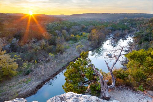 Sun sets in the distance with Barton Creek and the Barton Creek Greenbelt in the foreground