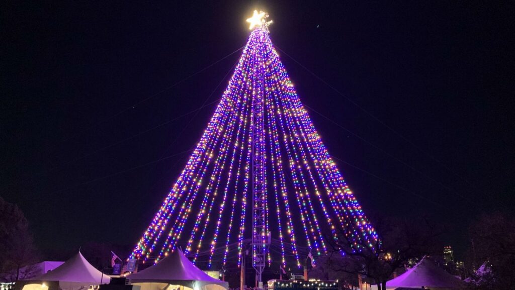 Tree made of lights with a star on top sits in Zilker Park at night